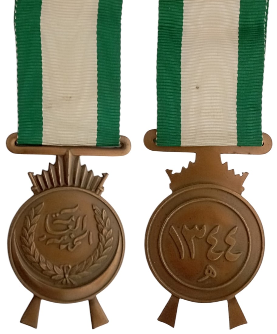 King Faisal’s War Medal (Nut al-Khidmat al-Amma), 1926, 2nd Model: Breast Badge, 55x35 mm, Bronze, original suspension ring and ribbon. Mint stateI