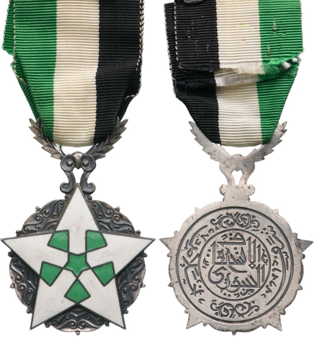 ORDER OF CIVIL MERIT: Knight's Cross, instituted in 1926. Breast Badge, 62x44 mm, silvered, one-side enameled, five-pointed, white and green enameled star of elaborate geometric design, with decorative designs between the 