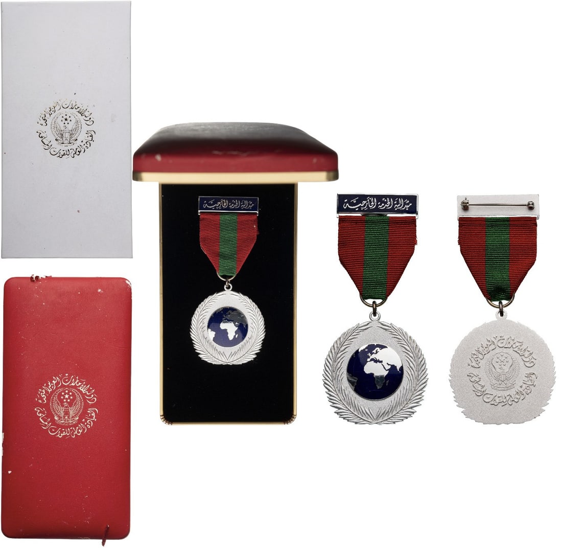 Foreign Service Medal, by Fattorini: Breast Badge, 50x47 mm, silvered, one-side enameled, original suspension ring and ribbon with ornamented and enameled suspension bar. A rare medal, in case of issue with gilt weapon on the lid and car