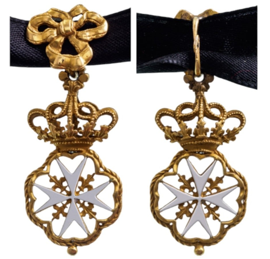 Sovereign Order of Malta: A Knight’s Cross of the Order in Gold with white enameled arms, flanked by fleurs de lys, enclosed in an elaborate frame of artistically bent and twisted gold wire, ending with a small sphaerical ap