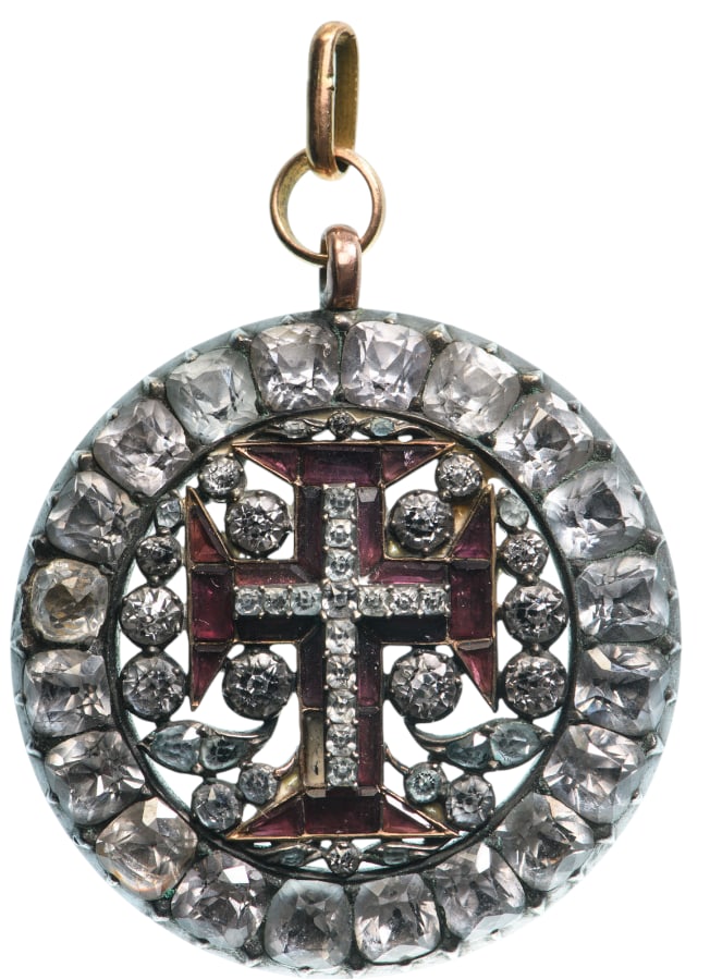 Military Order of Christ: A badge of the Order in the form of a round medallion, centered by the Order’s cross set with red and white stones, resting on a background of white stones, some of them forming a pattern of stylize