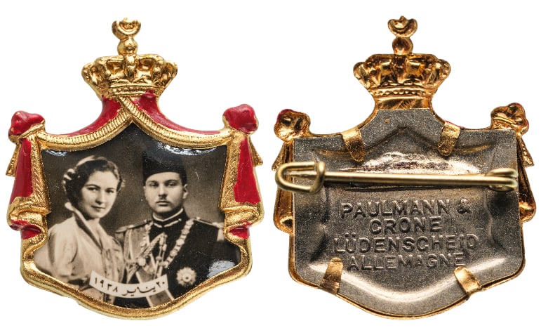 Royal Mariage Badge of King Farouk and Queen Farida, 20th of January 1938: Breast Badge, 28x23 mm., gilt Brass, obverse enameled, maker's mark "PAULMANN & CRONE, LUDENSCHEID - ALLEMAGNE", original horizontal pin on reverse. A very rare and attractive badge, of best German je