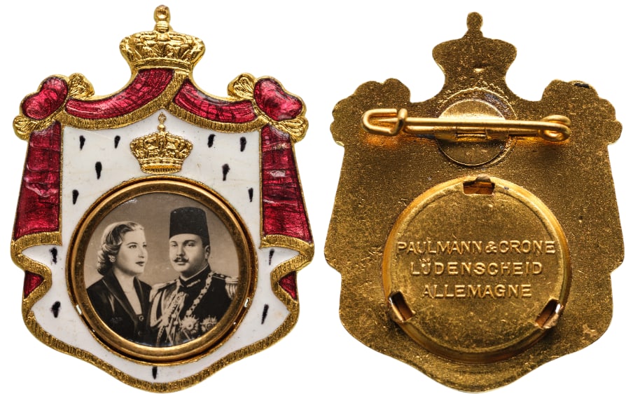 Royal Mariage Badge of King Farouk and Queen Narriman Sadek, 1951: Breast Badge, 28x23 mm., gilt Brass, obverse enameled, maker's mark "PAULMANN & CRONE, LUDENSCHEID - ALLEMAGNE", original horizontal pin on reverse. A very rare and attractive badge, of best German je