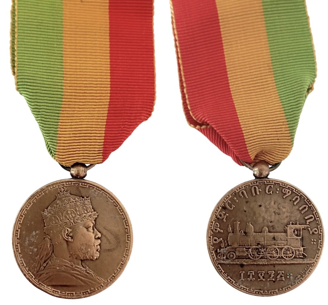 Menelik II Commemorative Medal Opening the Ethio-Djibouti Railway, by J.C. Chaplain and H. Patey,: Breast Badge, 37x32 mm, gilt Bronze, original suspension ring and ribbon. Extremely fine and attractive! I