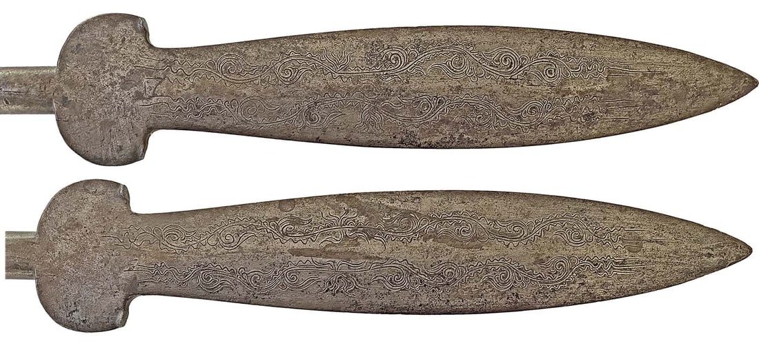 A Spear-head: Made of Iron, with tongue-shaped blade of flattened lens section, broadening at the base into two short side-wings, the blade, engraved with a pattern of foliage and stylized ornaments on both faces, 