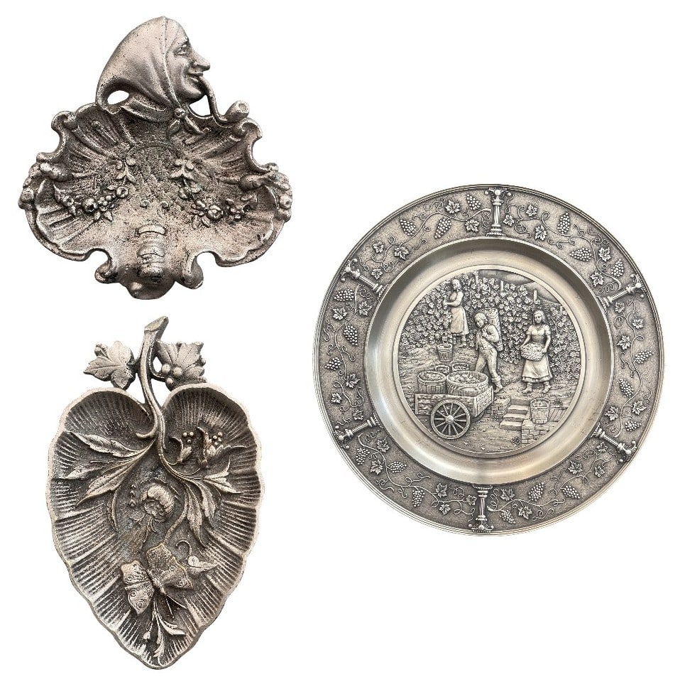 Lot of 3 objects: 1, Art Nouveau metal tray with a scalloped, leaf-like shape and raised floral motifs. At the top, it features a relief portrait of a figure in profile wearing a jester-style hood with a tied chin