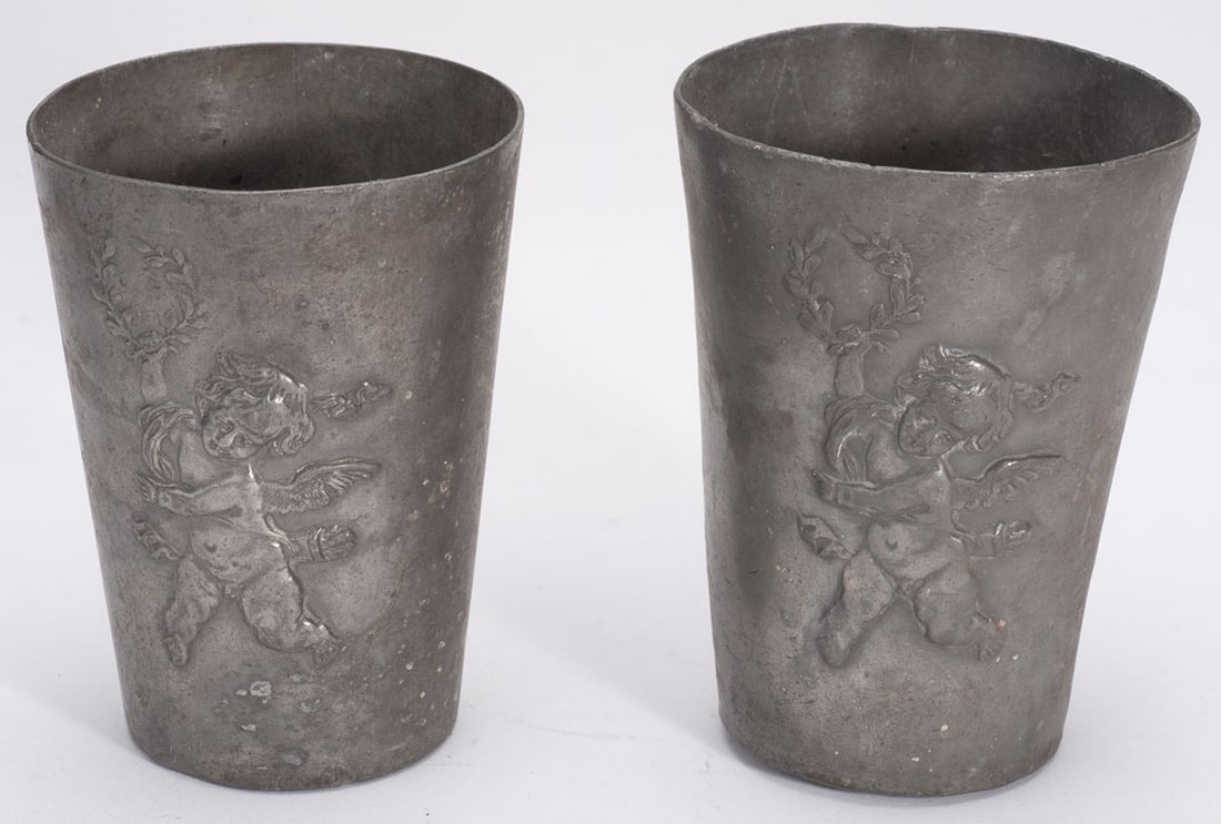 Pair of tin tumblers: Conical shape, Cupid subject engraved in relief on the body. Height 9 cm. Work old in the nineteenth, probably France.