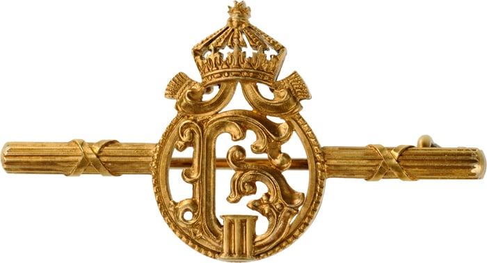 Brooch with the Royal Cypher of Tsar Boris III: Elaboralely made, crowned monogram of the King, 22,4x12,5 mm. GOLD, within round, beaded frame, mounted to a horizontal, grooved golden bar enriched by crossed ribands; fitted with thin, round pin wit