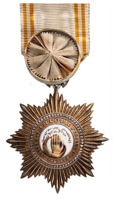 Order of the Star of Anjouan: Officer's Cross, 4th Class, instituted in 1874. Breast Badge, 63x57 mm., gilt Silver, central medallion gilt, enameled, original suspension ring and ribbon with rosette. A badge in extremely fine cond