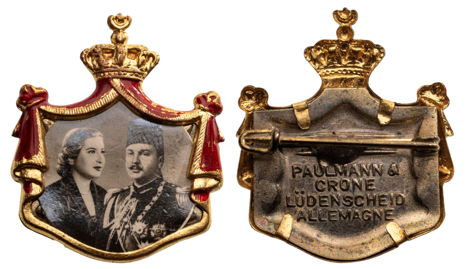 ROYAL MARIAGE BADGE OF KING FAROUK AND QUEEN FARIDA, 20TH OF JANUARY 1938: Breast Badge, 28x23 mm., gilt Brass, obverse enameled, maker's mark "PAULMANN & CRONE, LUDENSCHEID - ALLEMAGNE", original horizontal pin on reverse. A very rare and attractive badge, of best German je