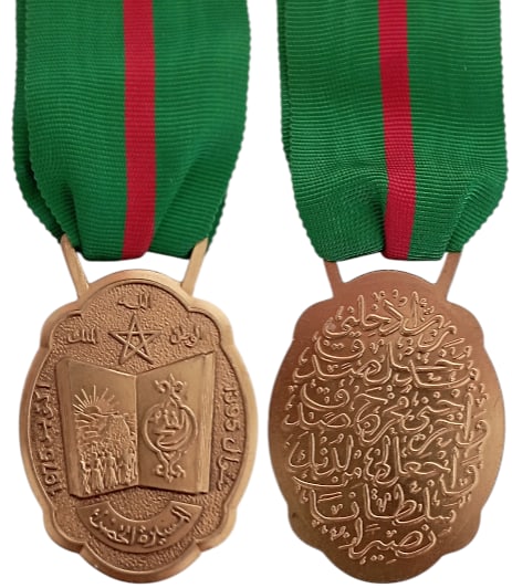 Medal of the Green March (Wissam al-Massira), instituted by King Hassan II, on the 17th of Novemeber: Breast Badge, 44x33 mm., gilt Bronze, original suspension ring and ribbon. An interesting medal, awarded to the civilians who participated at the march to Occidental Sahara, in November 1975. I