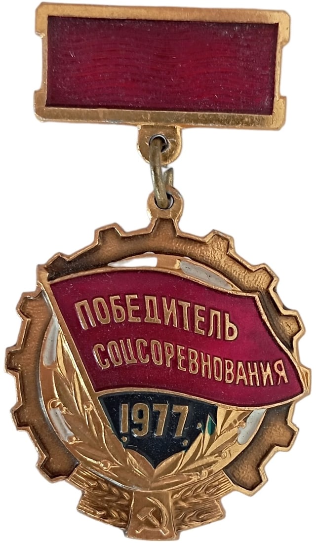 The Social Emulation Winner Award Badge, dated 1977: Breast Badge, 55x31 mm, gilt Copper, obverse partially enameled, original suspension ring and metallic ribbon. I