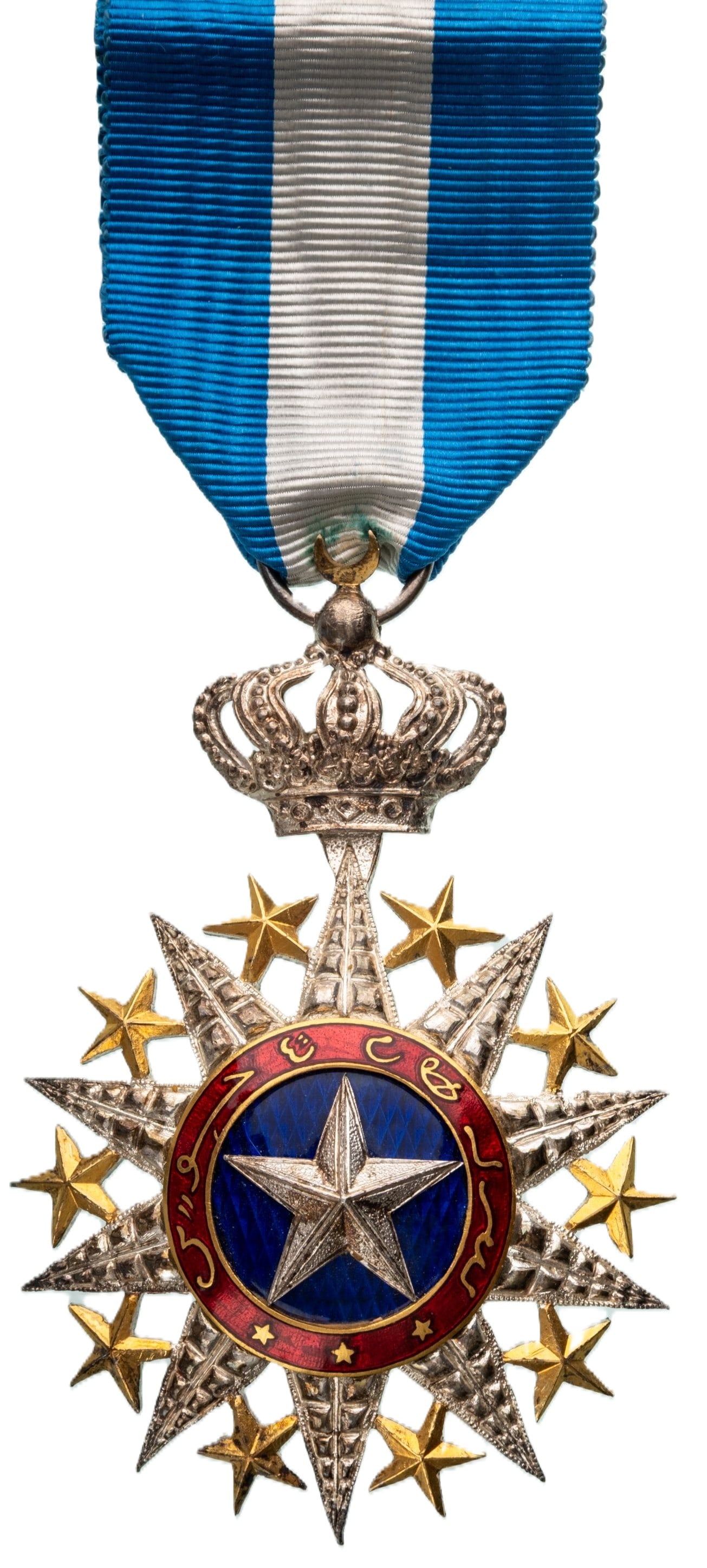Order Nichan el Anouar (Order of the Light) INSTITUTED by Hamed ben Mohamed, Sultan of Tadjourah: Officer's Cross, 4th Class, instituted in 1887. Neck Badge, 76x52 mm, partially gilt Silver, center enameled, original ornamented suspension crown, ring and ribbon. A rare and attractive badge, in ext