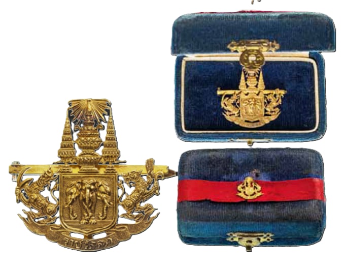 A Royal Gift Tie-pin: Breast Badge, 34x32 mm., GOLD, approx. 7.7 g. as the embossed and chiseled Thailandâ??s coat of arms, mounted on a horizontal gold bar fitted with pin to the reverse; in the original, blue velvet pre