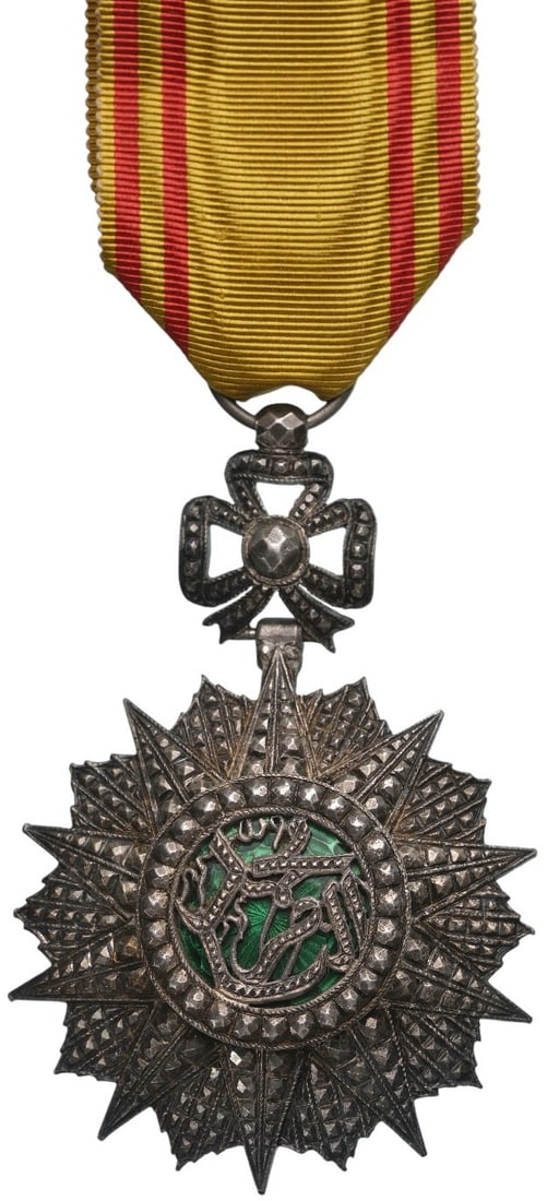 ORDER OF NICHAN AL IFTIKHAR: Knightâ??s Cross, 5th Class, Mohamed el Naceur (1905â??1922). Knightâ??s Badge, 74x48 mm, Silver, partially enameled, original suspension ring and ribbon.A superb jeweller's quality, in extremely f