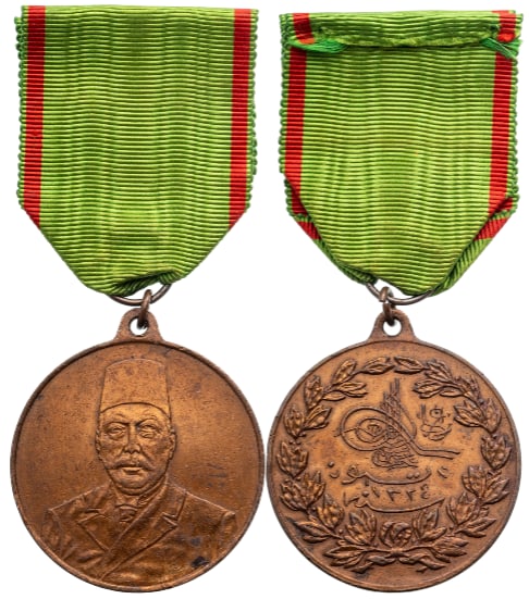 Constitutionnal Medal (Mehmet Resat Han), 1913: Breast Badge, 44x40 mm, Bronze, original suspension ring and ribbon. A very large sized medal, in extremely fine condition. I.
