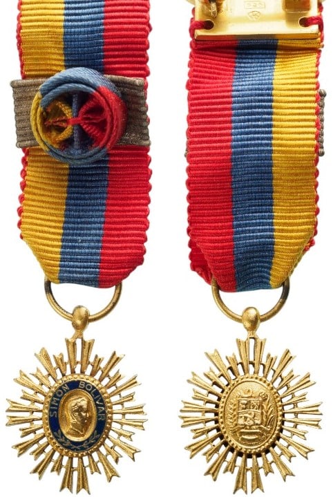 Order of the Libertador, instituted in 1880: Commander's Cross Miniature, 3rd Class. Breast Badge, 20x15 mm., gilt Bronze, original suspension ring and ribbon with rosette and silver bar and reverse suspension pin. A scarce miniature, in mint co