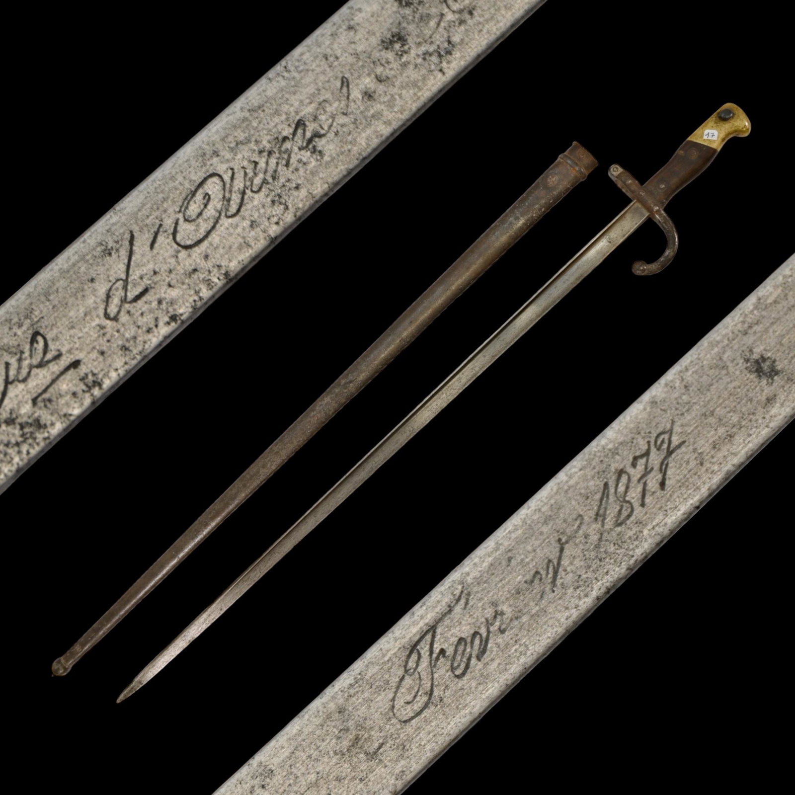French Model 1874 Gras rifle bayonet and scabbard, date 1877: French Model 1874 Gras rifle bayonet and scabbard, date 1877. This bayonet has a solid brass pommel with integral latching mechanism (push-button/spring-steel). Grips are wood. Crossguard is steel wit