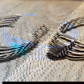Turquoise Silver Bracelet: This turquoise silver bracelet is uniquely designed. Multiple strands of silver interweave to form the bracelet body, exuding a sense of simplicity and layers. A square turquoise stone is inlaid in th