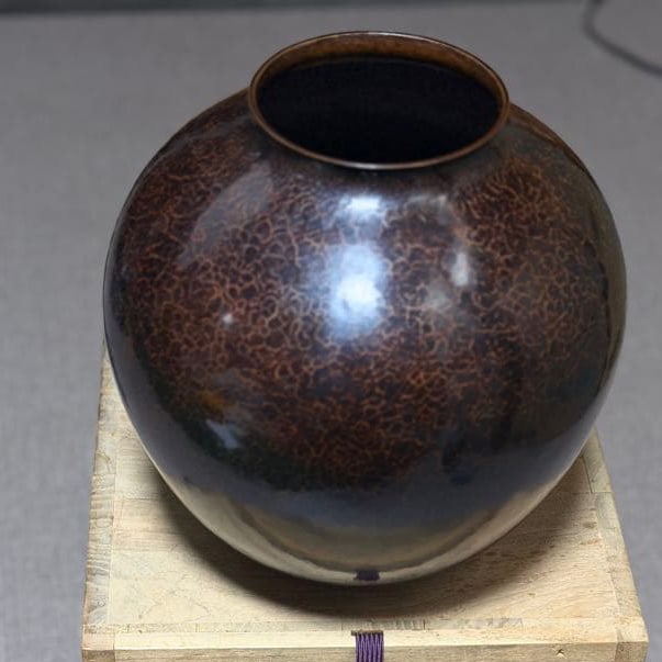 Takahashi Shigehiro hand-hammered copper round vase, with wooden box, 1960s: A brown and black copper round vase adorned with crackle patterns, accompanied by a wooden box.Delicate and exquisite patterns are pleasing to the eye.The surface of this wood carving work features a