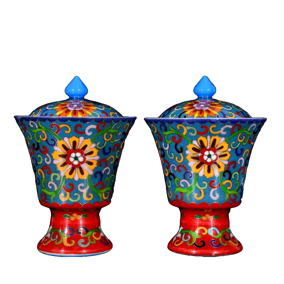 A pair of high-stem cups with cloisonné enamel floral design of the Qianlong era: This pair of blue-ground famille-rose enameled high-foot cups from the Qianlong period is of great artistic value. The body of the cup features a blue background adorned with colorful floral designs a