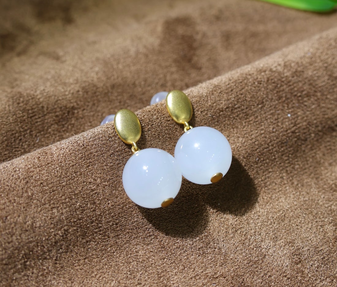18K gold natural Hetian jade earrings: These earrings showcase the eternal beauty of Hetian white jade, renowned for its luster and delicate texture. The jade is carefully crafted into a simple yet elegant design, perfect for those who