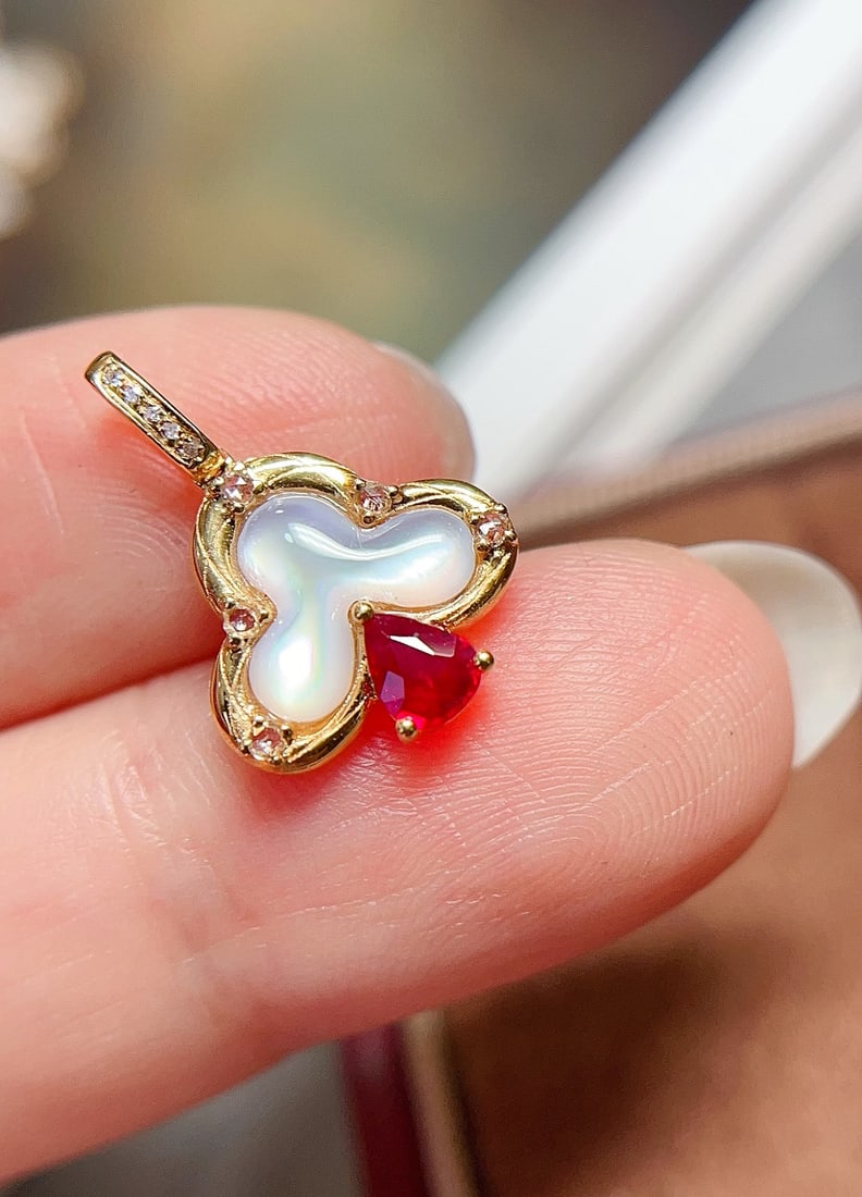 18K Gold Natural Ruby Pendant: This pendant perfectly combines the fiery charm of natural rubies with the understated elegance of mother-of-pearl elements. At its center is a ruby of approximately 0.25 carats, while five sparkling