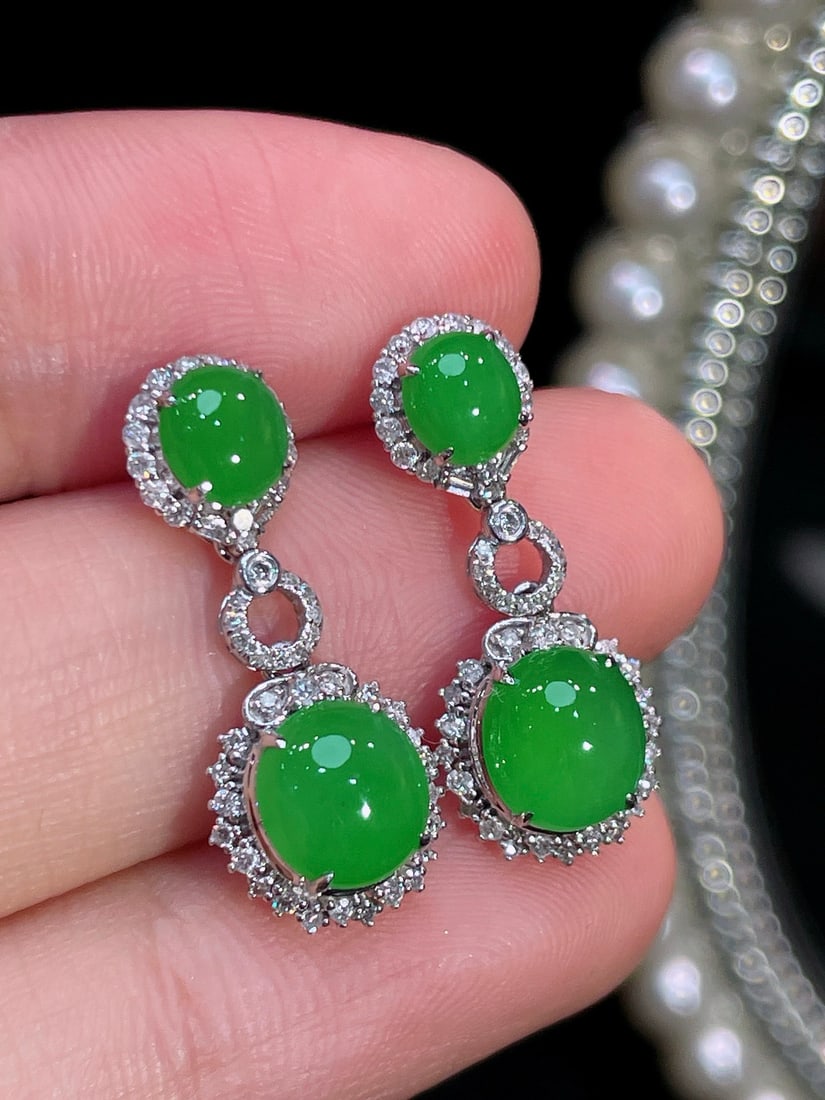 18k Gold Jadeite Earrings: This exquisite pair of earrings features a dazzling full green oval cabochon as its centerpiece, cleverly set in 18k gold. Delicate diamonds surrounding the full green stone add a touch of brilliance,
