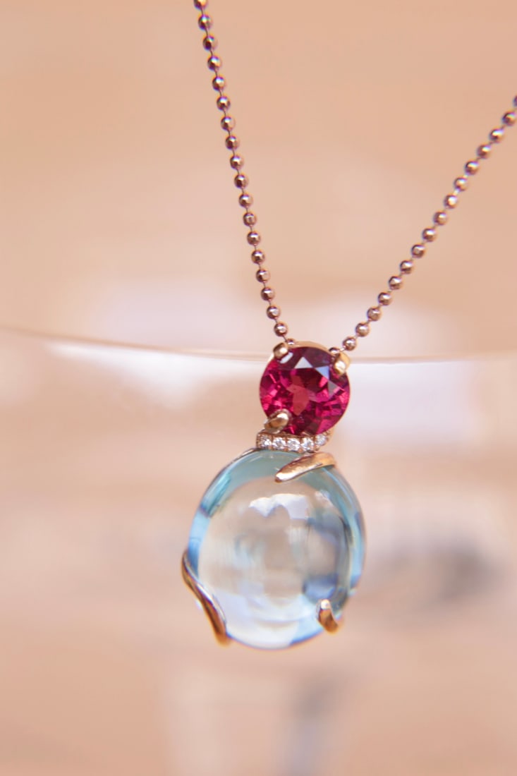 18K gold pomegranate topaz diamond pendant: This 18K gold pomegranate topaz diamond pendant, with its simple and elegant design, perfectly showcases the wearer's nobility and grace. The main stone, pomegranate, weighs 12.05 carats, with a beaut