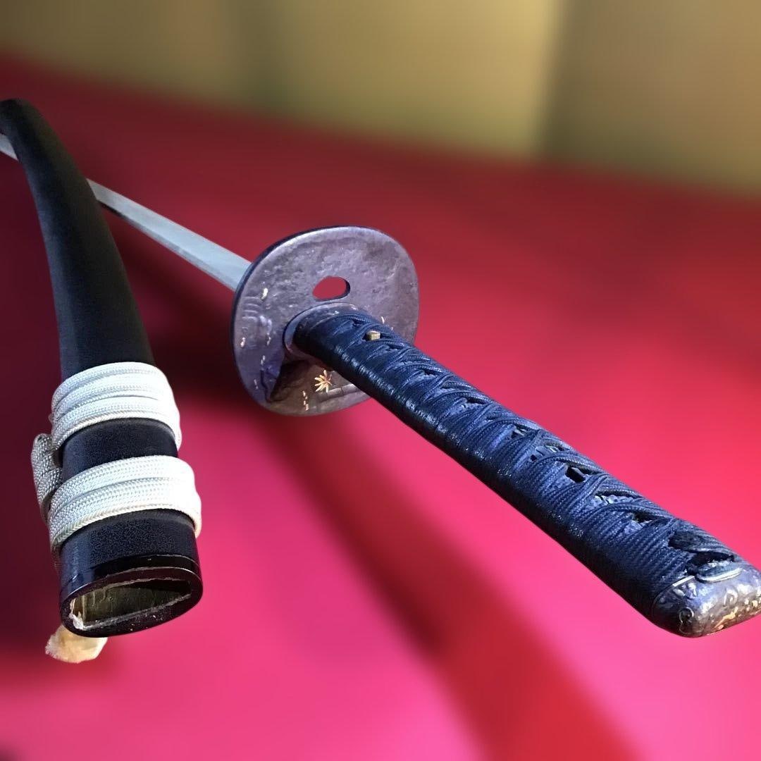 Edo Period Long Sword (DaitO) – Iron Ground with Gold Inlay Mountings, Large Tsuba: A long sword (daitO) from the Edo period, mounted with iron fittings featuring gold inlay decoration (tetsuji kinzOgan koshirae). The mountings display refined metal craftsmanship, highlighted by a