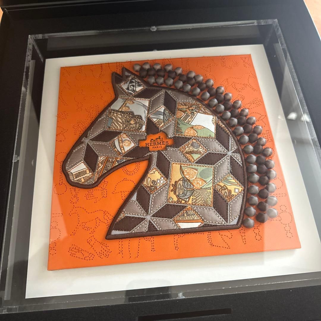 HERMES – Horse Head Design Art (Brand New, Extremely Rare)-second hand: Product Details Brand: HERMES Design: Horse head motif Color: Orange & Brown Material: Fabric with leather-like accents Embellishments: Bead detailing Dimensions: Approx. 30cm × 30cm Frame: Acrylic e