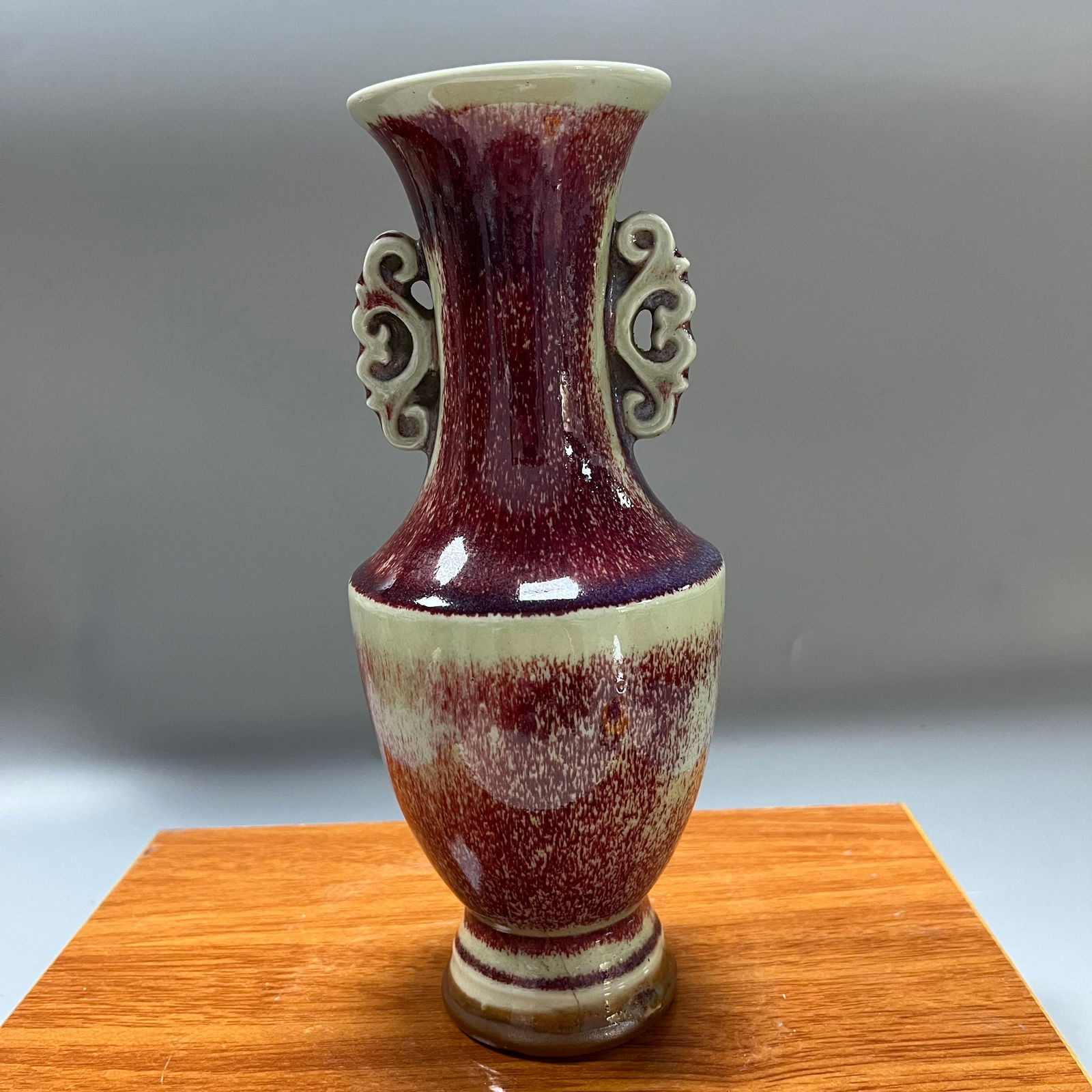 Late Qing Dynasty Jun Red Kiln Transformation Glazed Double-Eared Openwork Vase: This is a late Qing dynasty kiln-transformed glaze vase with two handles, measuring 23 x 9.5 cm, with an elegant and dignified shape. The vase features a flared mouth, slender neck, full shoulders, an
