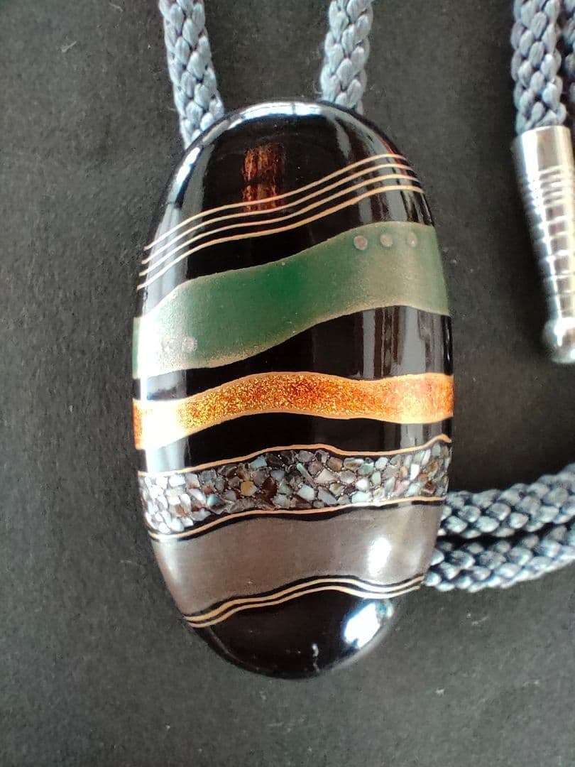 (Second-hand) Vintage polo tie, black and green stripes, glass/mosaic decoration: This is a well-designed retro circular necktie. The shiny top cover has a black base color. Decorated with green and gold lines, this is a unique piece of art, very eye-catching, adorned with mosaic-s