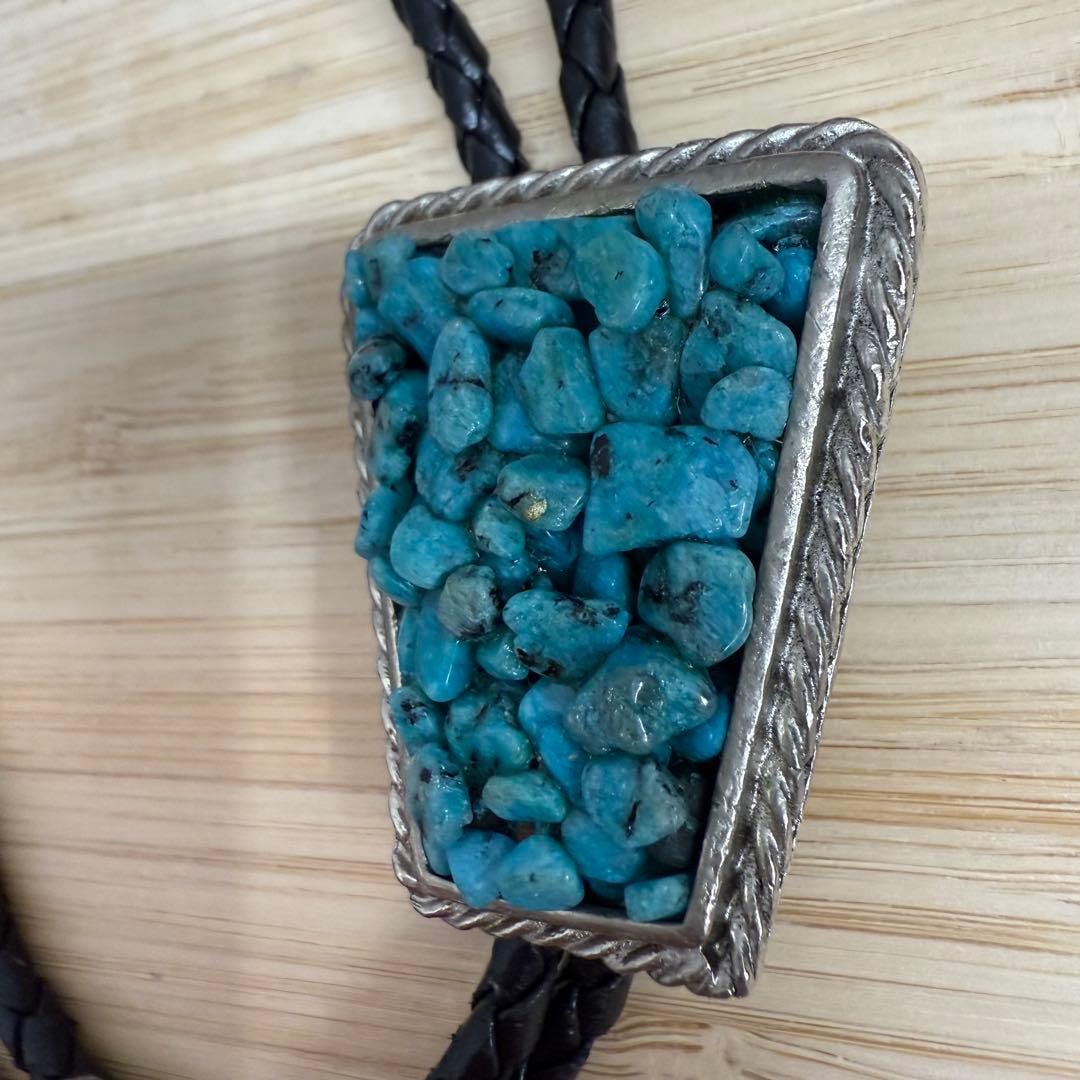 (Second-hand) Silver circular tie clip with turquoise: A circular necktie with a silver triangular pendant adorned with a green turquoise gemstone. Color: Black Material: Turquoise, Silver Design: Triangular pendant Style: Casual Length: Adjustable