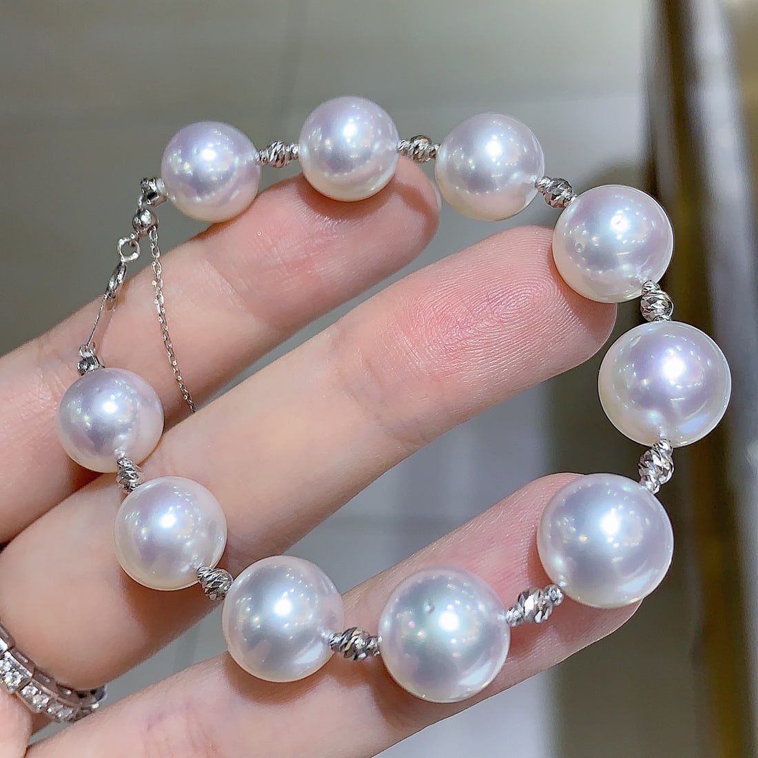 Pearl Bracelet: This bracelet exudes a sense of sophistication with its lustrous white pearls, each measuring 11-12mm in diameter. The pearls are perfectly round, exhibiting a subtle aurora-like sheen that captures t