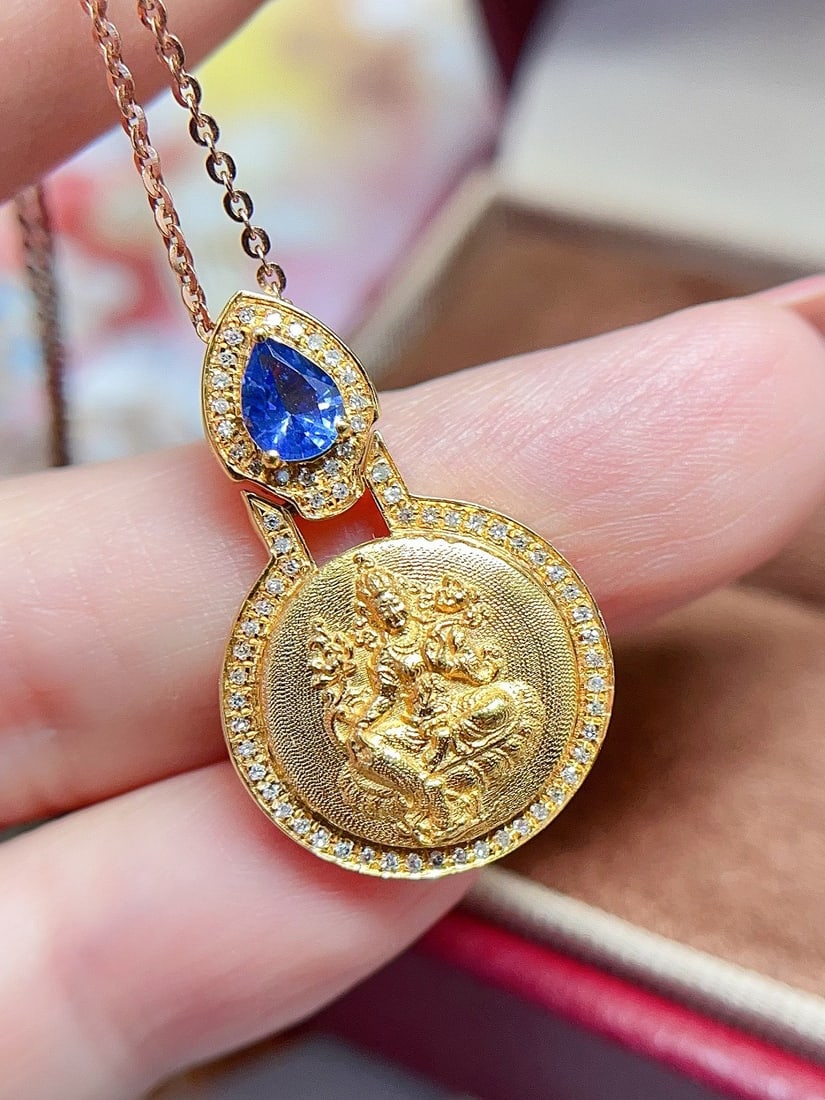 18K Gold Sapphire Pendant: This pendant captures the essence of elegance with its exquisite sapphire centerpiece. The sapphire, reminiscent of a delicate cornflower, is set in a luxurious gold coin design, offering a unique