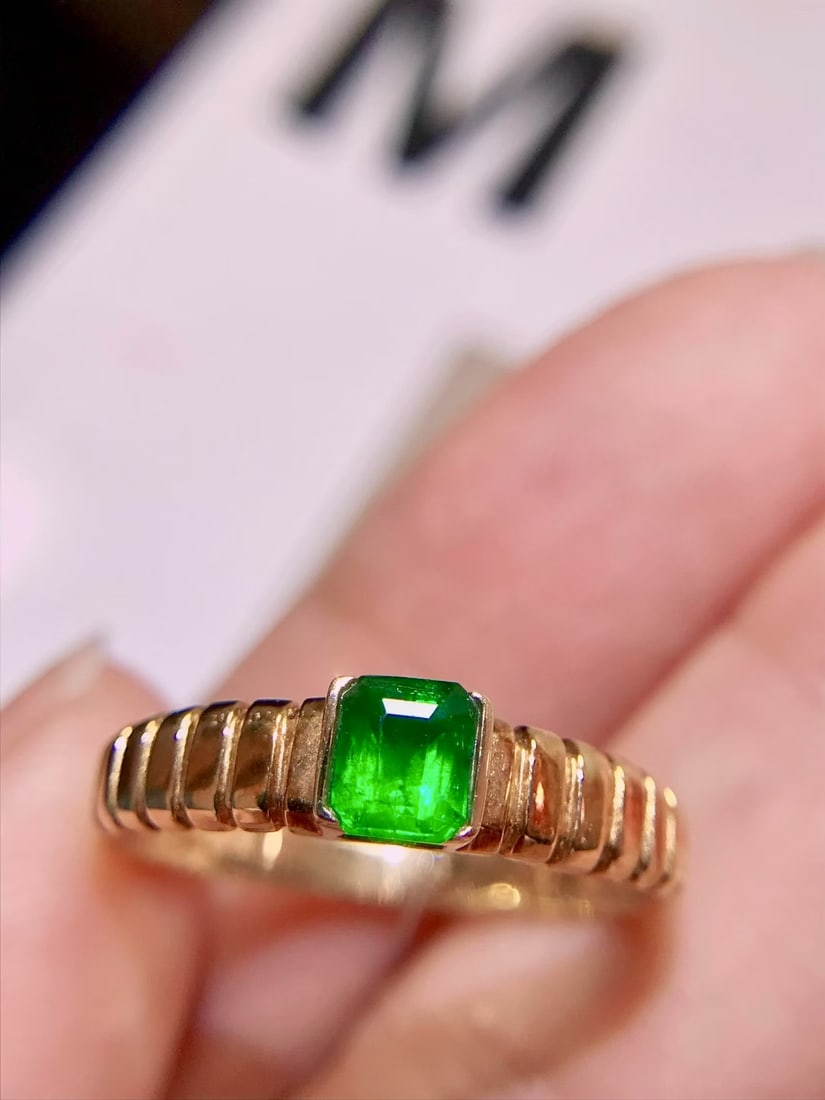 18K Gold Emerald Ring: This 18K Gold Emerald Ring is a testament to timeless elegance and versatility. Its vivid green emerald captivates with a refreshing simplicity, making it a perfect staple for any wardrobe. The