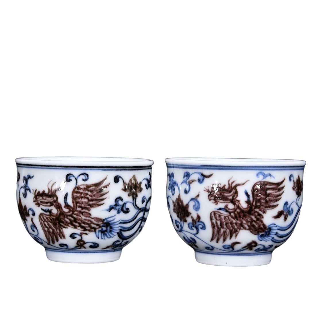 A pair of Ming Xuande blue and white porcelain cups with underglaze red phoenix pattern.: This Ming Xuande blue and white cup with underglaze red phoenix pattern is 5.5 cm tall and 7 cm in diameter. The shape of the cup is thick and dignified, with a slightly contracted mouth and a low rin