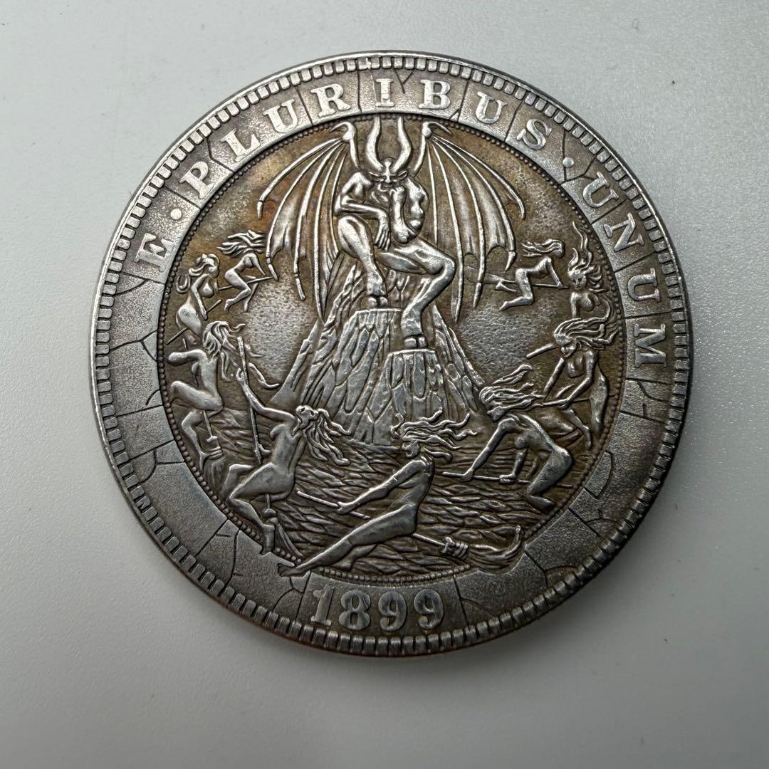 1899 antique coin, devil commemorative medal: This is a commemorative medal from 1899.At the center is a figure resembling a demon with outstretched wings, standing on top of a rocky mountain, surrounded by other figures, creating a unique and st