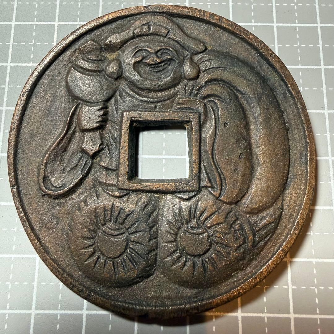 Ancient coin, with a large black sky pattern.: Extra-large sized coin with a smiling image of the God of Wealth on the back, and the four treasures on the reverse side. It is a lucky charm and mascot for collectors.