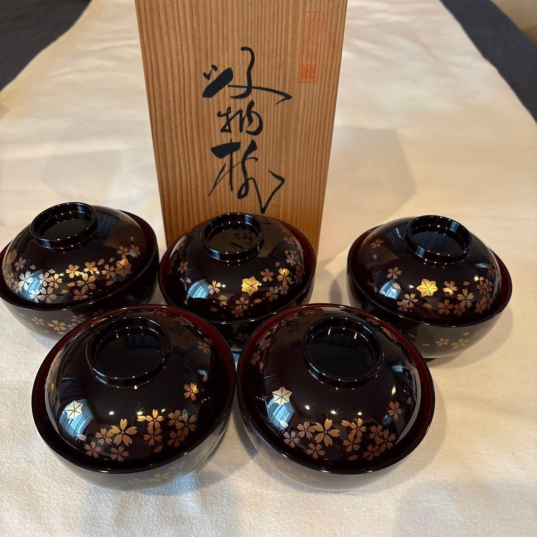 A set of 5 cherry blossom patterned lacquer bowls.: A set of five lacquerware pieces, decorated with gold foil and cherry blossom patterns.