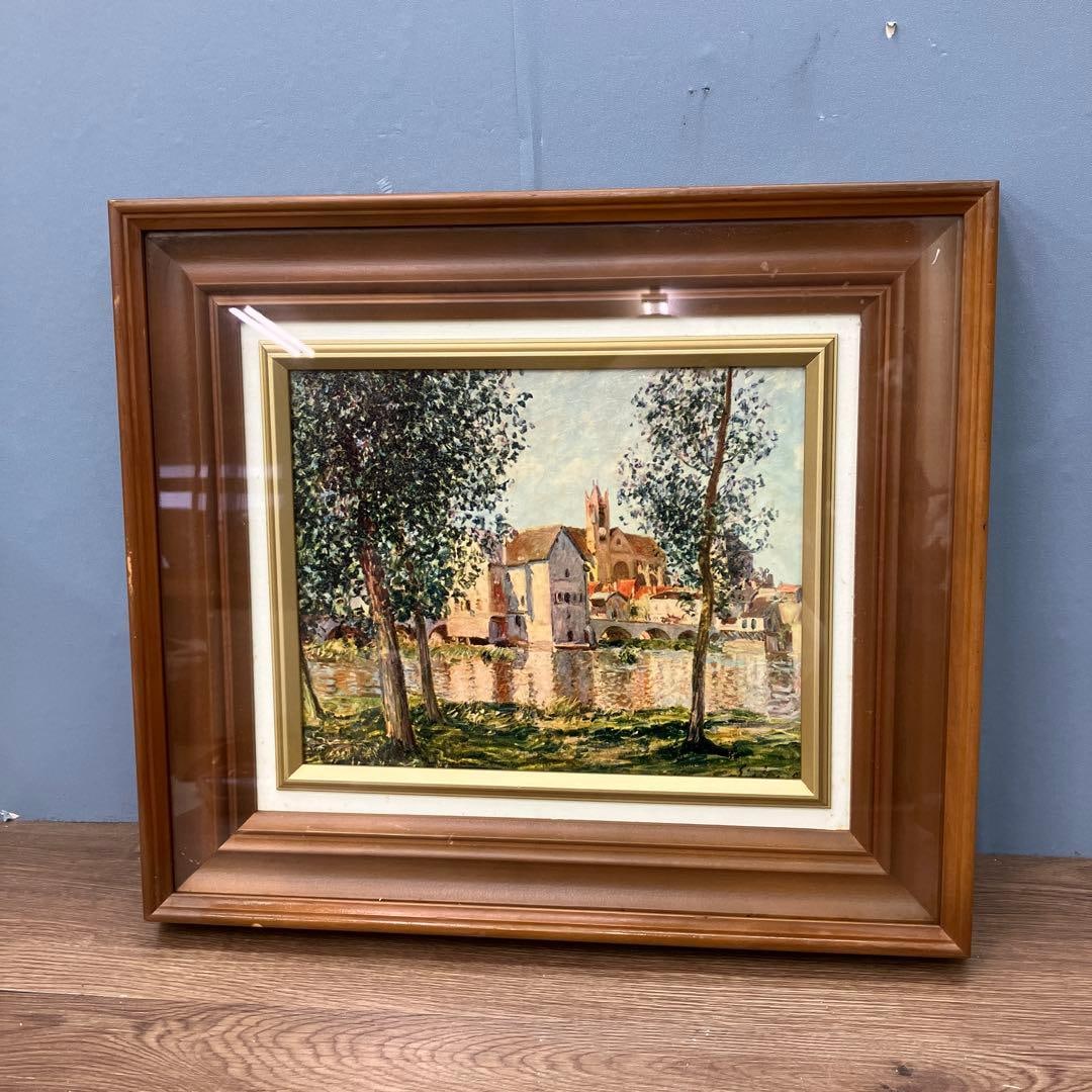 Landscape painting, oil painting: This is a captivating landscape painting depicting a gently flowing river and a town with a long history.The painting is framed in a thick and sturdy wooden frame, showcasing a luxurious texture. It i