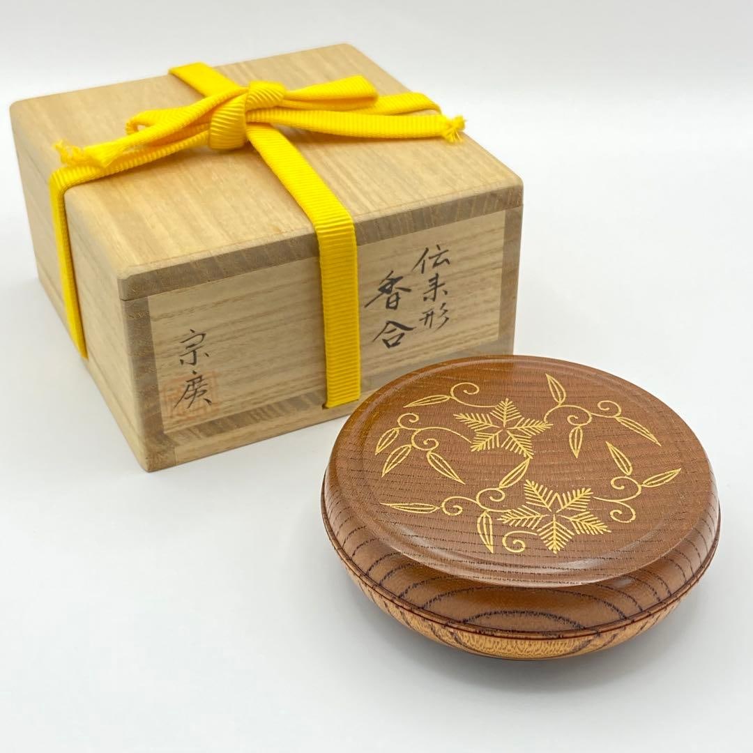A traditional style lacquer incense box crafted by DOjO SOkO.: A traditional style lacquer incense box crafted by DOjO SOkO, adorned with pine, bamboo, and Arabesque patterns, accompanied by the original box. Dimensions: Diameter 8.8 cm, Height 2.7 cm