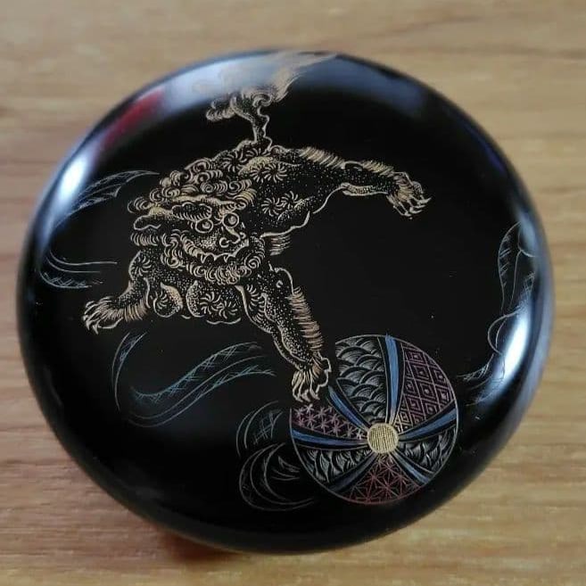 Incense Box/Small Container, Black Lacquer Finish, Adorned with Lion and Temari Ball Motifs.: Design: Black lacquer finish, adorned with a gold lion motif Shape: Round incense box (with lid) Signature: Artist's signature on the bottom. No packaging box Diameter: Approximately 7 cm Thickness: A