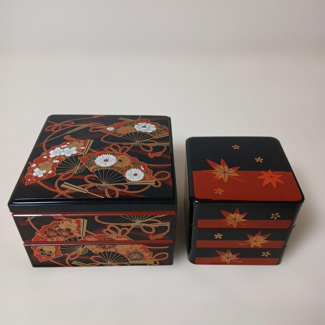 A set of multi-tiered bento boxes, black background, decorated with gold and red patterns. (1 of 7)