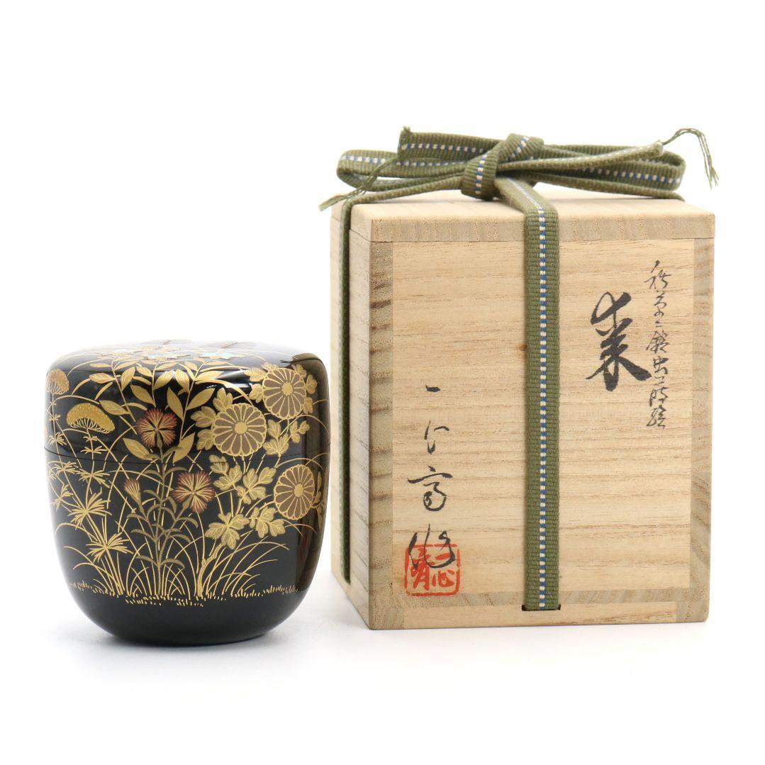 A tea caddy by Okutsu Isshin-sai, decorated with maki-e lacquerware, featuring a design of autumn: A tea caddy by Okutsu Isshin-sai, decorated with maki-e lacquer, featuring a design of autumn grasses and crickets, inlaid with mother-of-pearl and adorned with a pattern of blue shell. Accompanied