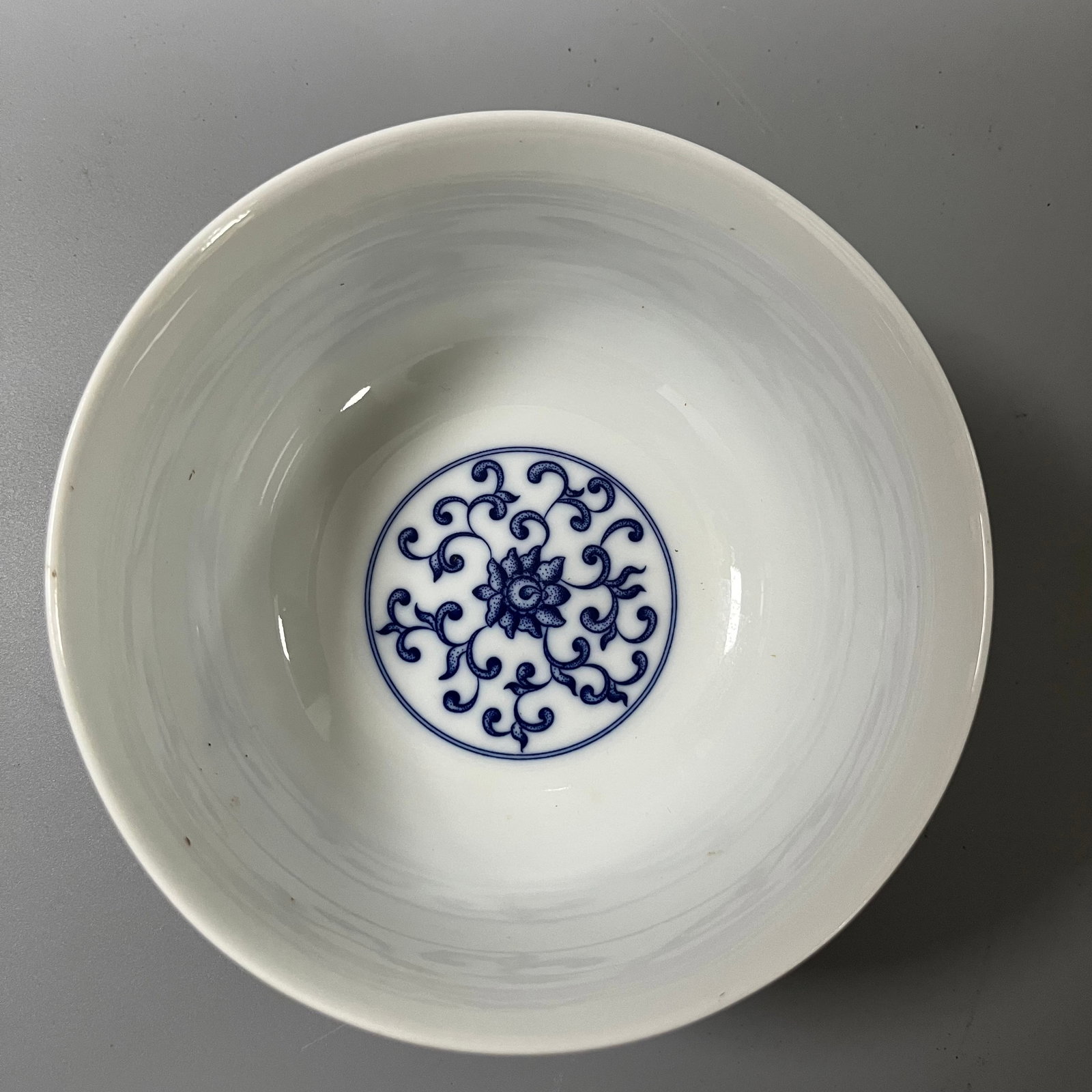 A blue and white porcelain bowl with a light-colored lotus scroll design from the Qianlong period of: This Qing dynasty blue-and-white bowl with a lightly painted lotus scroll design measures approximately 13.5cm in diameter and 7cm in height. It has a regular shape, with a flared rim, curved belly, a