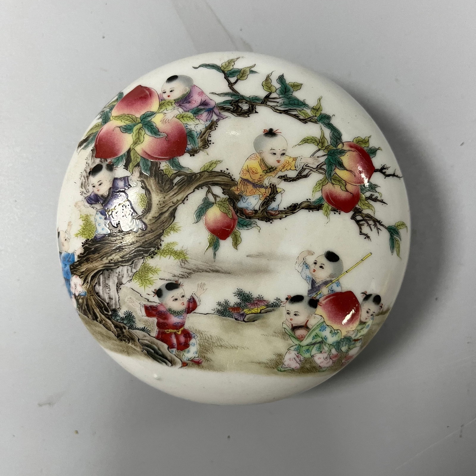 A famille rose inkpad box/rouge box from the Qianlong period of the Qing Dynasty: This Qing dynasty famille rose inkpad box with a children's play motif, also known as a rouge box, measures approximately 12cm in diameter and 4cm in height. Its exquisite form consists of a lid and b