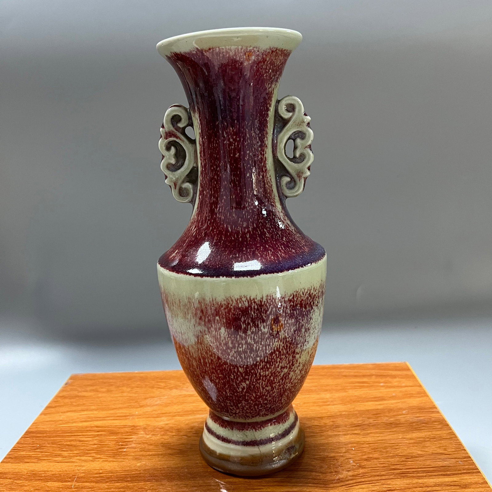Late Qing Dynasty Jun Red Kiln Transformation Glazed Double-Eared Openwork Vase: This is a late Qing dynasty kiln-transformed glaze vase with two handles, measuring 23 x 9.5 cm, with an elegant and dignified shape. The vase features a flared mouth, slender neck, full shoulders, an