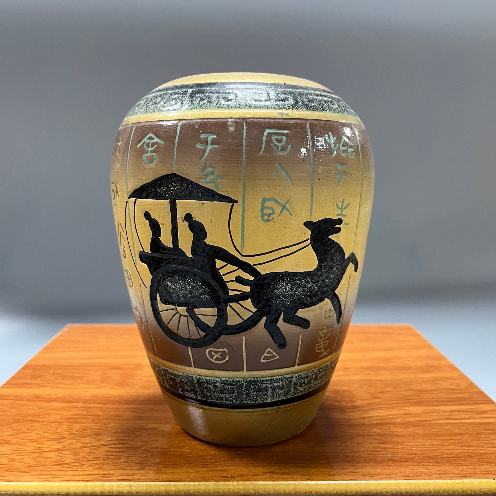 Pottery jar with chariot and horse design in bronze inscription: A pottery jar with a chariot and horse design in bronze inscription, 17 x 12 cm. The entire set of vessels has a robust shape, with geometric patterns on the rim and foot. The interior shows a delicat